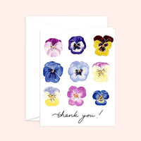 Thumbnail for Watercolor greeting card and white envelope featuring a grid of nine vibrant pansies in shades of purple, blue, and yellow with the handwritten text 