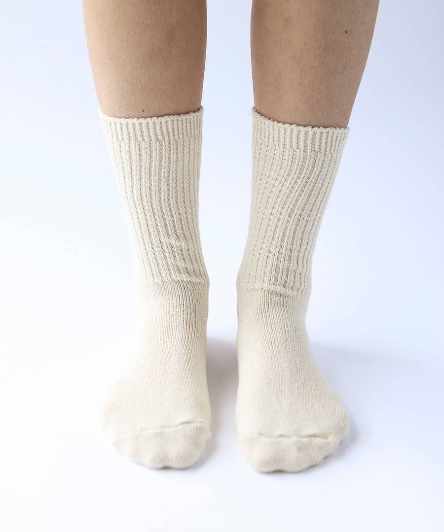Close-up of legs and feet in cream coloured ribbed cotton socks. 