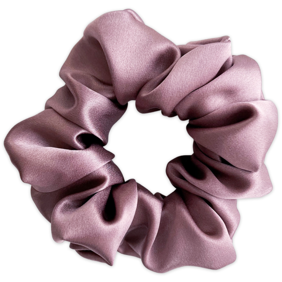 A mauve mulberry silk scrunchie, appearing soft and lustrous, is displayed against a white background with visible folds in the fabric.