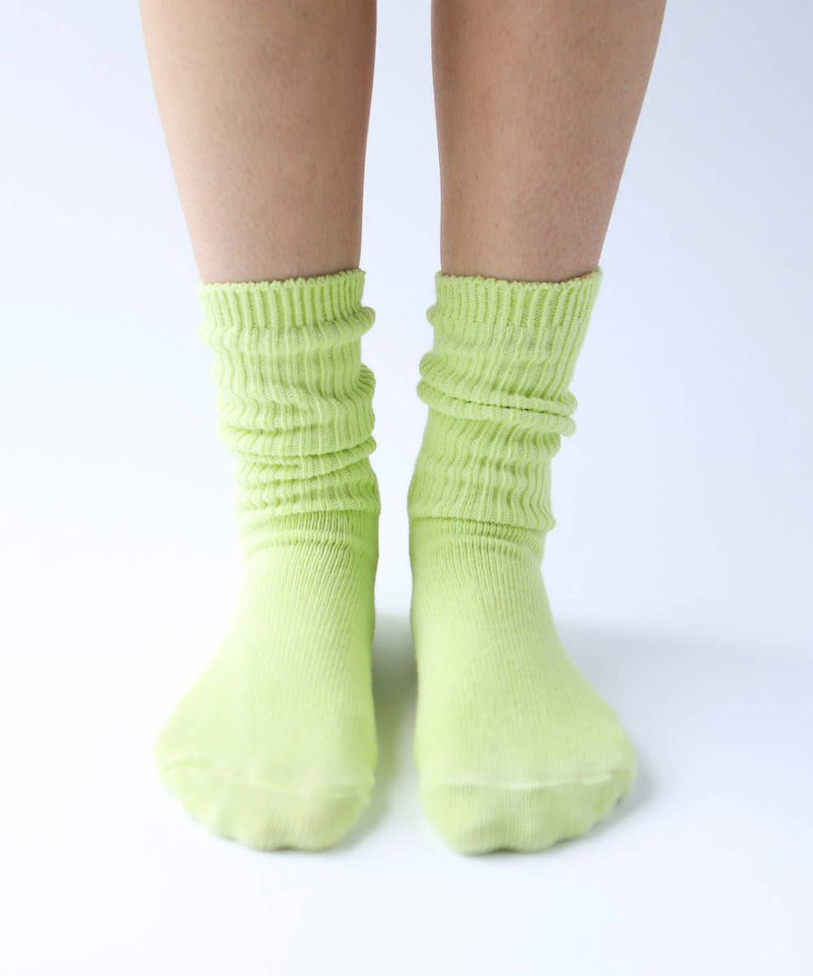 Close-up of legs and feet in pastel lime green ribbed cotton socks. 