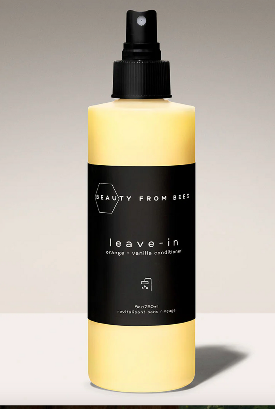 Yellow "Beauty From Bees" leave-in conditioner bottle with a black label reading "leave-in orange + vanilla conditioner".