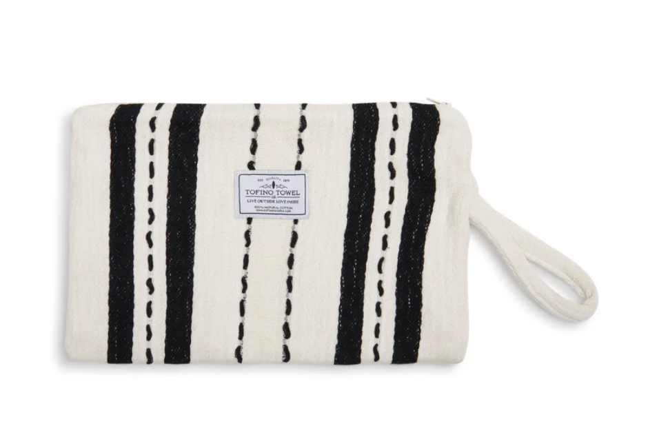 A front-facing flat lay of the Mercer Wet-Dry bag on a white background. The ecru (cream) Turkish Cotton exterior features thick, vertical black stripes with unique, hand-embroidered dashed line details. A centered "Tofino Towel Co." brand patch is visible, and a matching cream-colored woven wrist strap is attached to the right side.