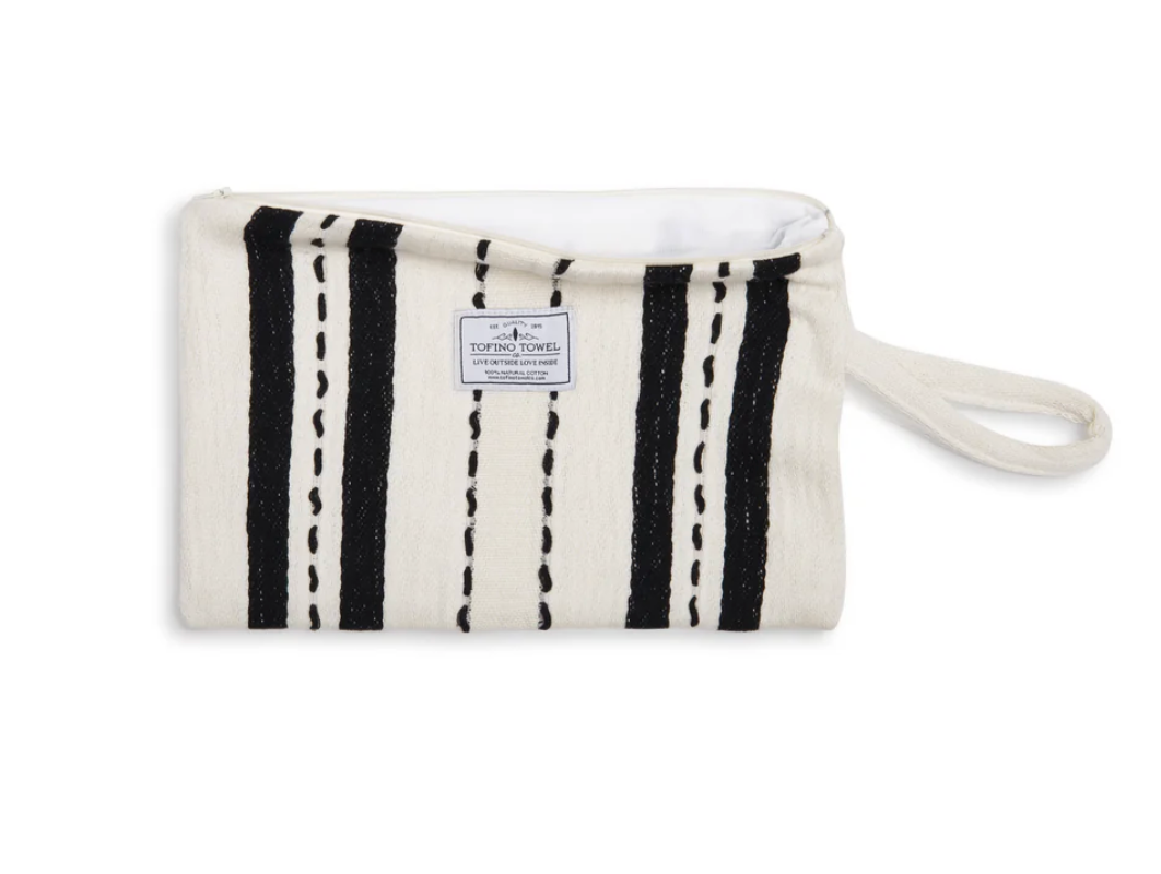 A flat lay of the ecru-colored Mercer bag unzipped, showing the white water-resistant interior lining and the "Tofino Towel Co." logo on the front.