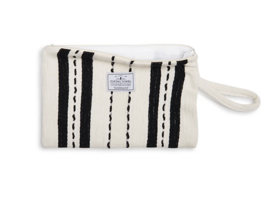 A flat lay of the ecru-colored Mercer bag unzipped, showing the white water-resistant interior lining and the "Tofino Towel Co." logo on the front.
