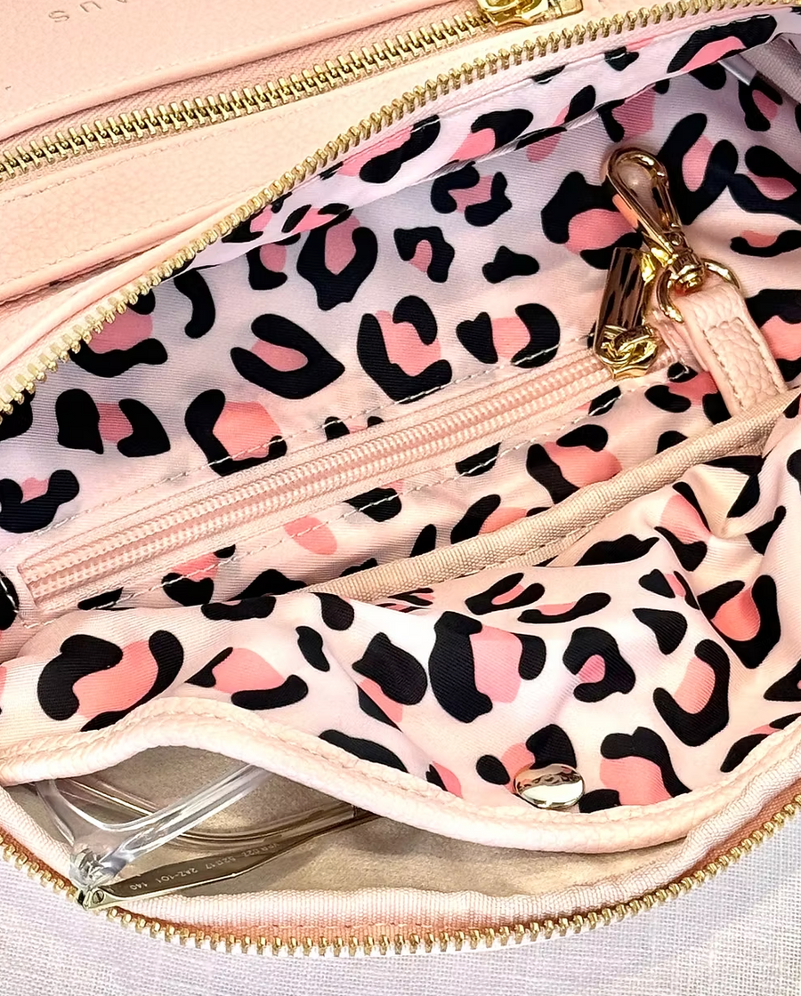 The inside of a pink bag with a pink and black leopard print lining.