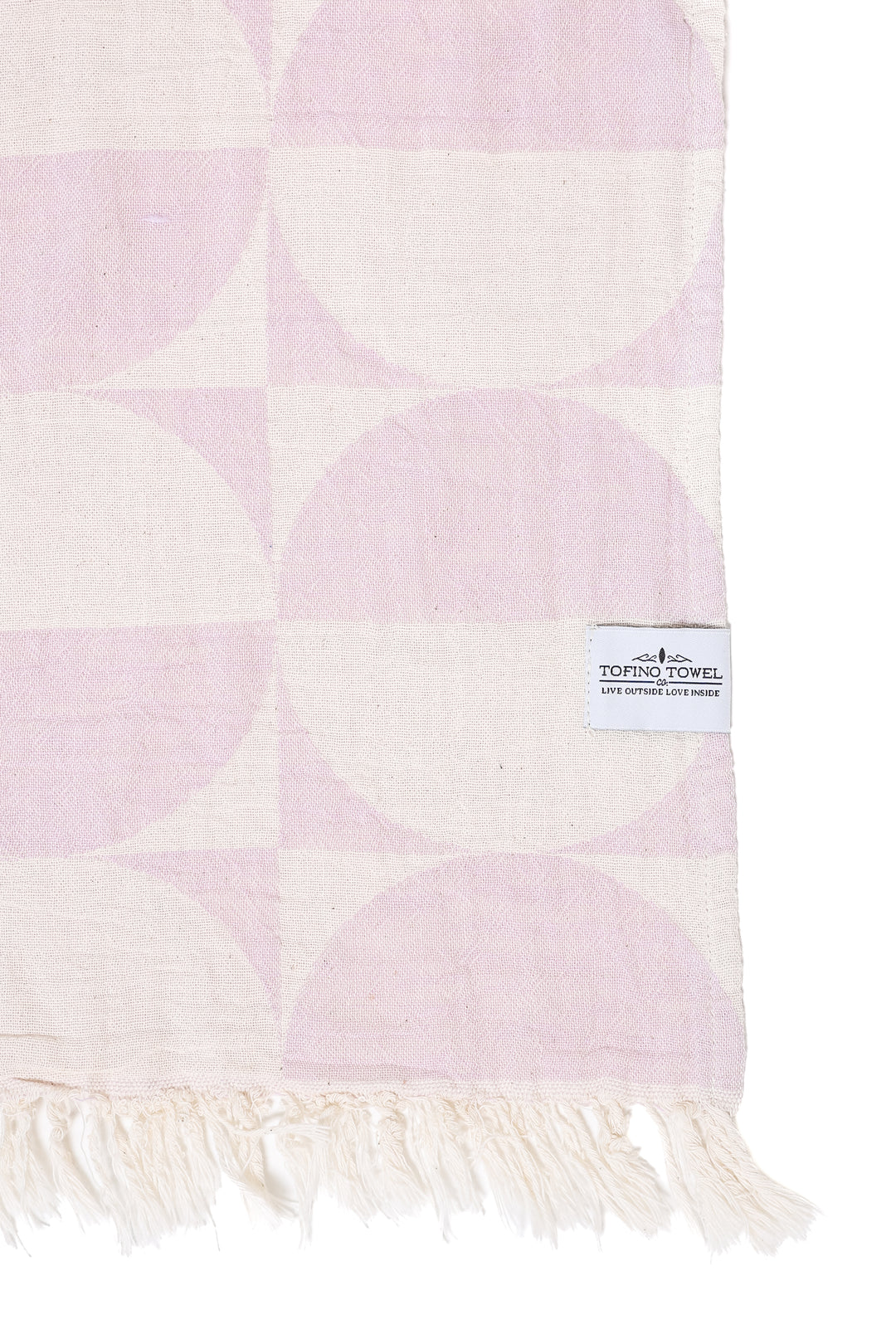 A close-up of the Phase towel in Lilac, showcasing the reversible jacquard weave. The pattern features geometric half-circles in a soft lavender and cream, finished with a white "Tofino Towel Co." brand label and cream-colored eyelash fringe.