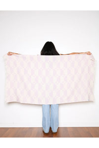 Thumbnail for A woman holding the lilac Phase towel spread wide across her back, showcasing its generous 160cm length and bold geometric circular pattern.