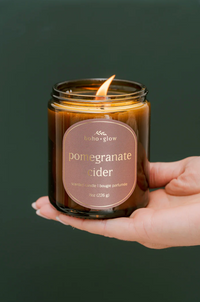 Thumbnail for 
A hand holds a lit amber jar candle by Boho + Glow labeled 