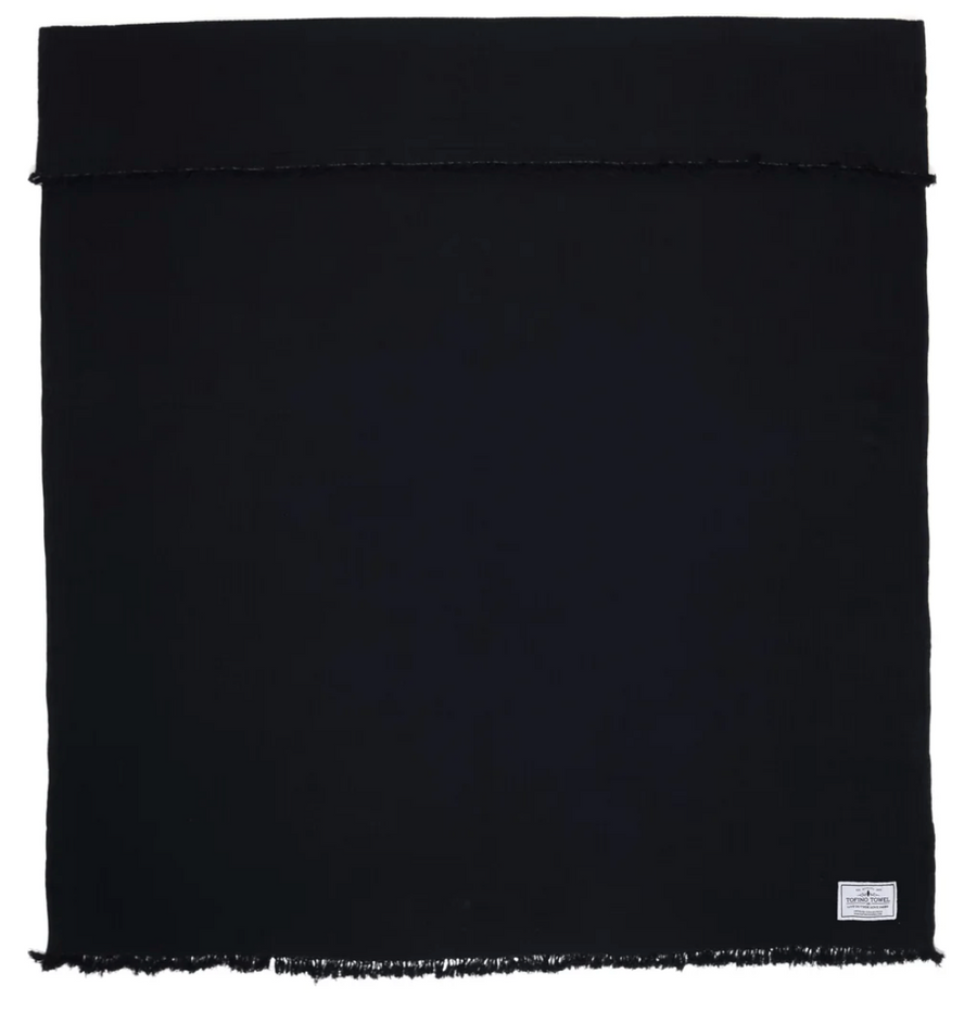 A black, rectangular Capella Muslin Throw with fringed edges is shown.