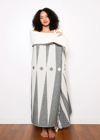 Thumbnail for A woman wrapped in a black and white patterned throw blanket.