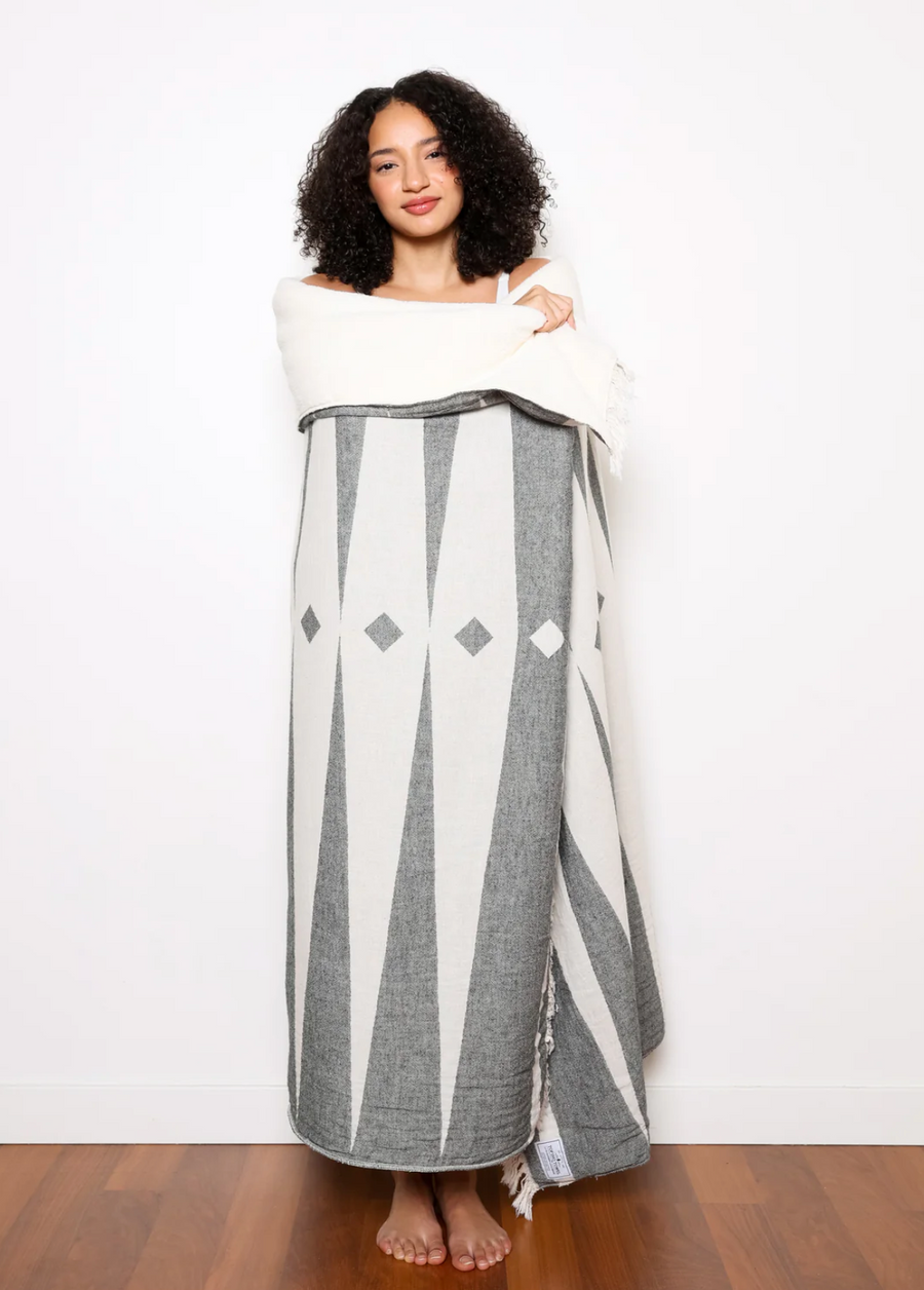 A woman wrapped in a black and white patterned throw blanket.
