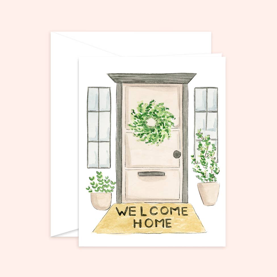 Watercolor greeting card and white envelope featuring an illustration of a front door with a green wreath, potted plants, and a "WELCOME HOME" doormat.
