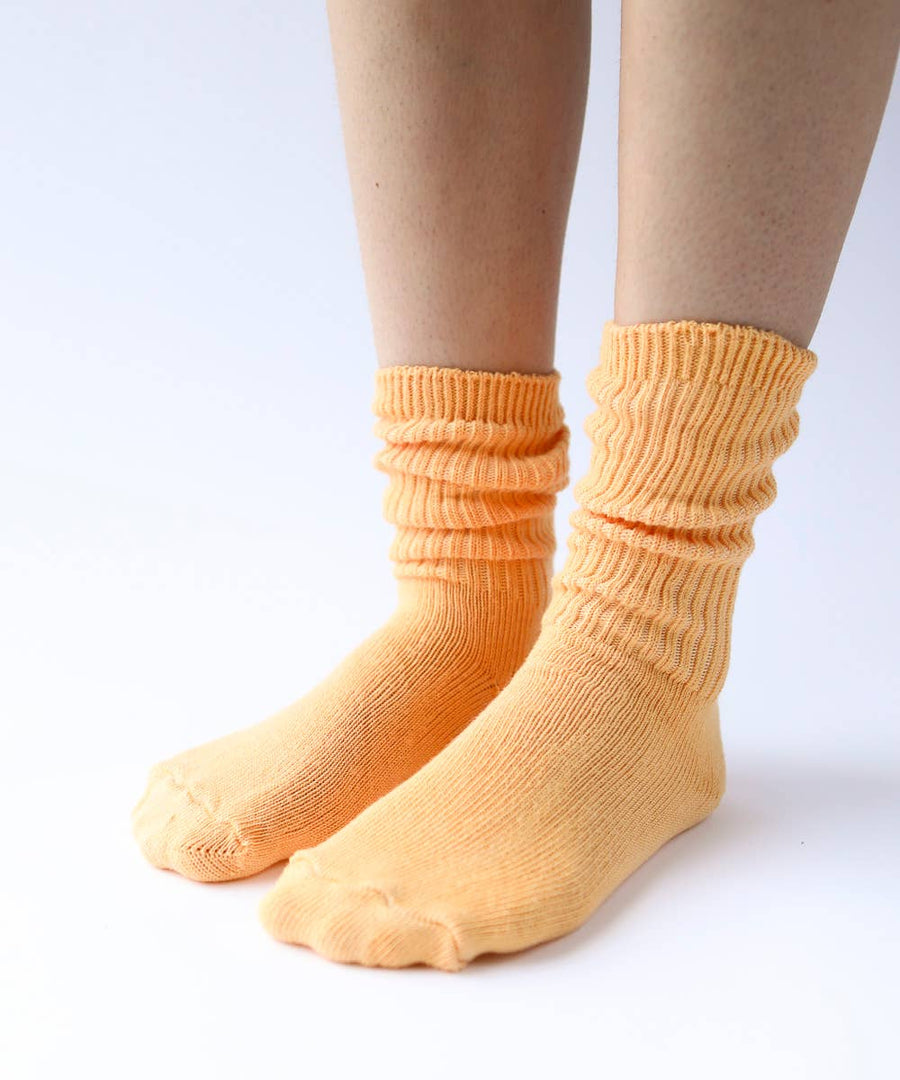 Close-up of legs and feet in soft, light orange ribbed cotton socks. 