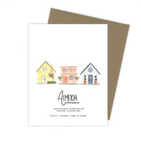 Thumbnail for The back of a greeting card with a kraft paper envelope, featuring three colorful watercolor houses and the Almeida Illustrations logo.
