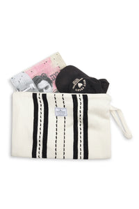 Thumbnail for A top-down flat lay of the large Ecru/Black striped Mercer bag. Inside the open zipper are a black baseball cap and a large magazine, showing the bag's ability to hold oversized travel or adventure essentials.