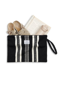 Thumbnail for A top-down flat lay of the large Black/Ecru striped Mercer bag, unzipped to show its large capacity. A pair of tan suede clogs, an open book, and a beige insulated water bottle are tucked inside, illustrating its size.